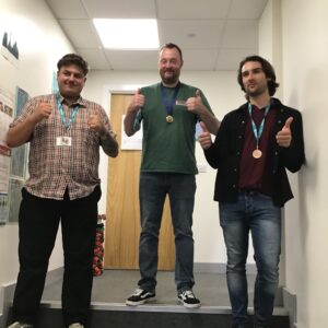 3 team members with thumbs up wearing medals