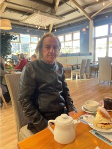 resident sitting at table with scone and pot of tea