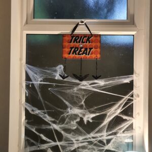Radcliffe House Halloween decorations: Trick or Treat sign hung on a window covered in fake cobwebs