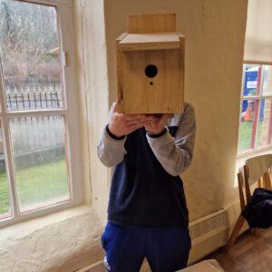 male holding wooden bird box
