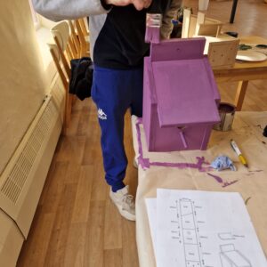 adding the finishing touches of purple paint to the bird box