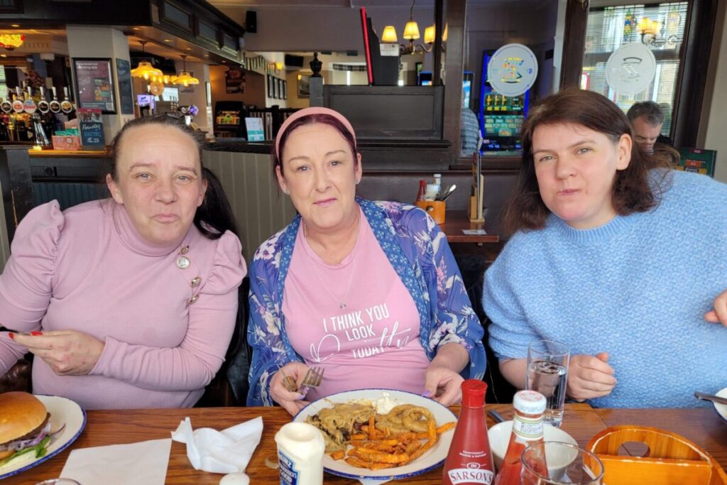 3 female sat at table with pub meal