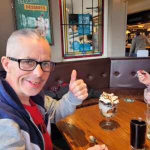 male with thumb up and ice cream sundae on table