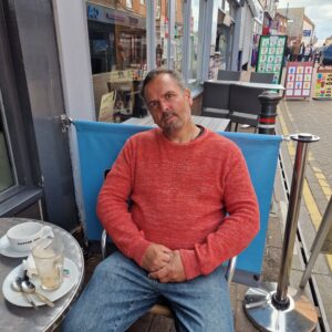 resident in red jumper sitting outside coffee shop
