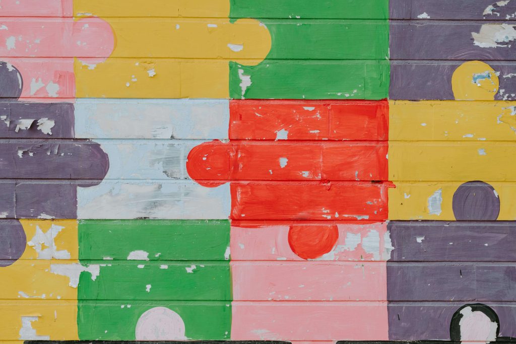 A wall painted like a multicoloured jigsaw puzzle for a blog about autism mental health and autism masking
