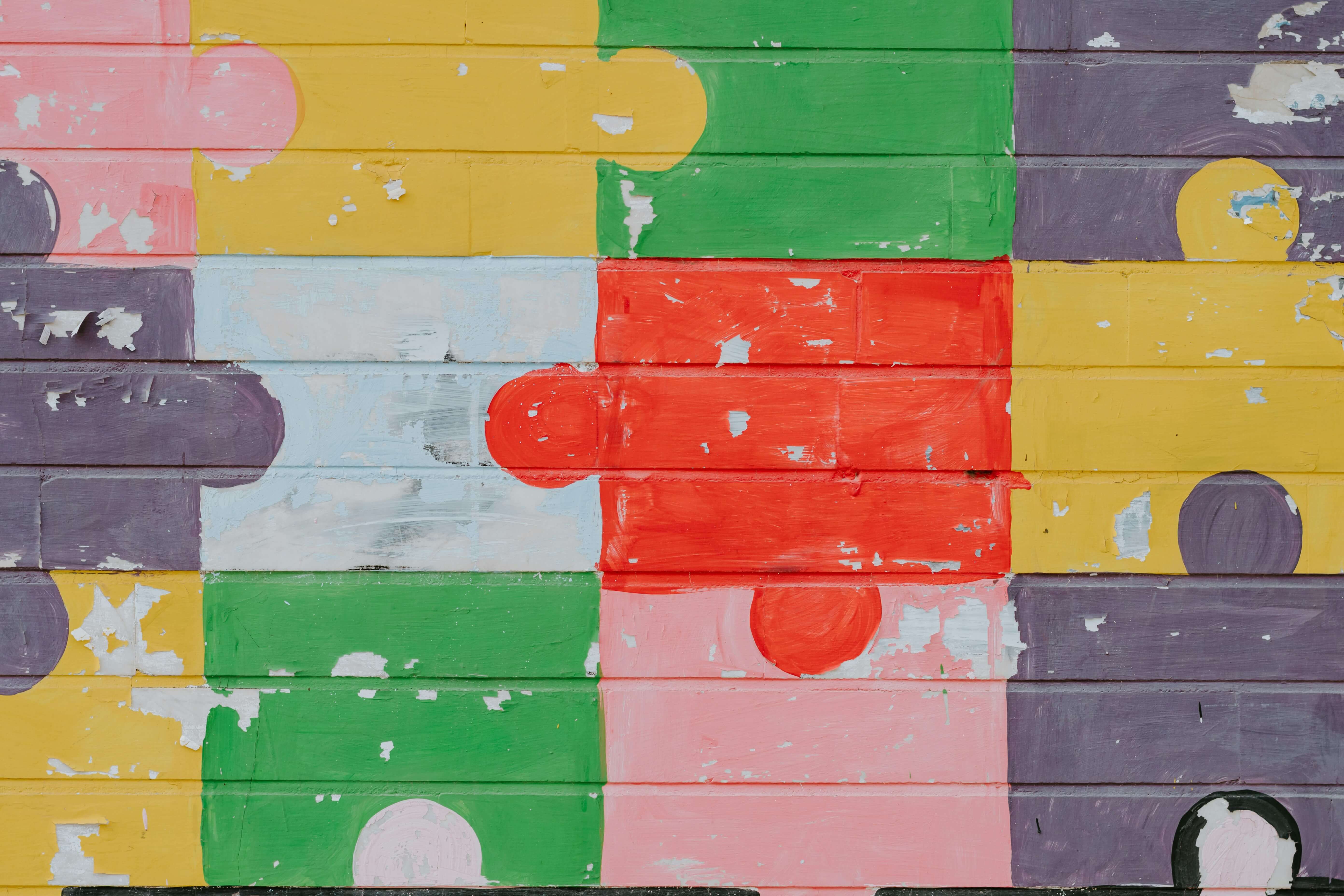 A wall painted like a multicoloured jigsaw puzzle for a blog about autism mental health and autism masking