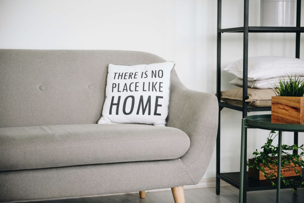 Living room with cushion spelling 'There's No Place Like Home' for a blog about supported living vs residential care for mental health.