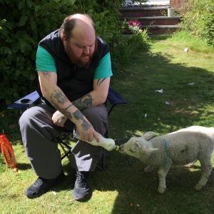 resident feeding a lamb from milk bottle