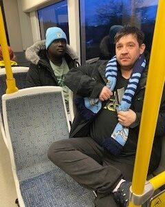 residents on the bus wearing Man City hats and scarves