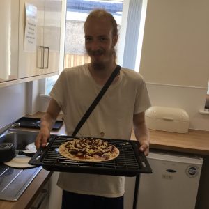 resident holding pizza ready for the oven