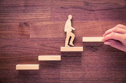 wooden depiction of man walking up stairs