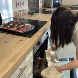 female putting cupcakes into oven