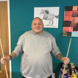 resident holding pool cues in each hand