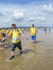 Glen Garth resisdents and staff walking along the beach through shallow sea water