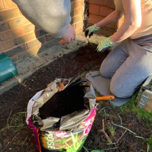 residents adding soil to flowerbed from bag of soil