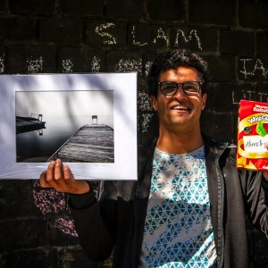 resident holding box of wine gums and black and white image of jetty