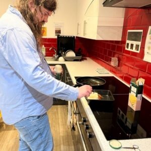 Male resident making lasagne