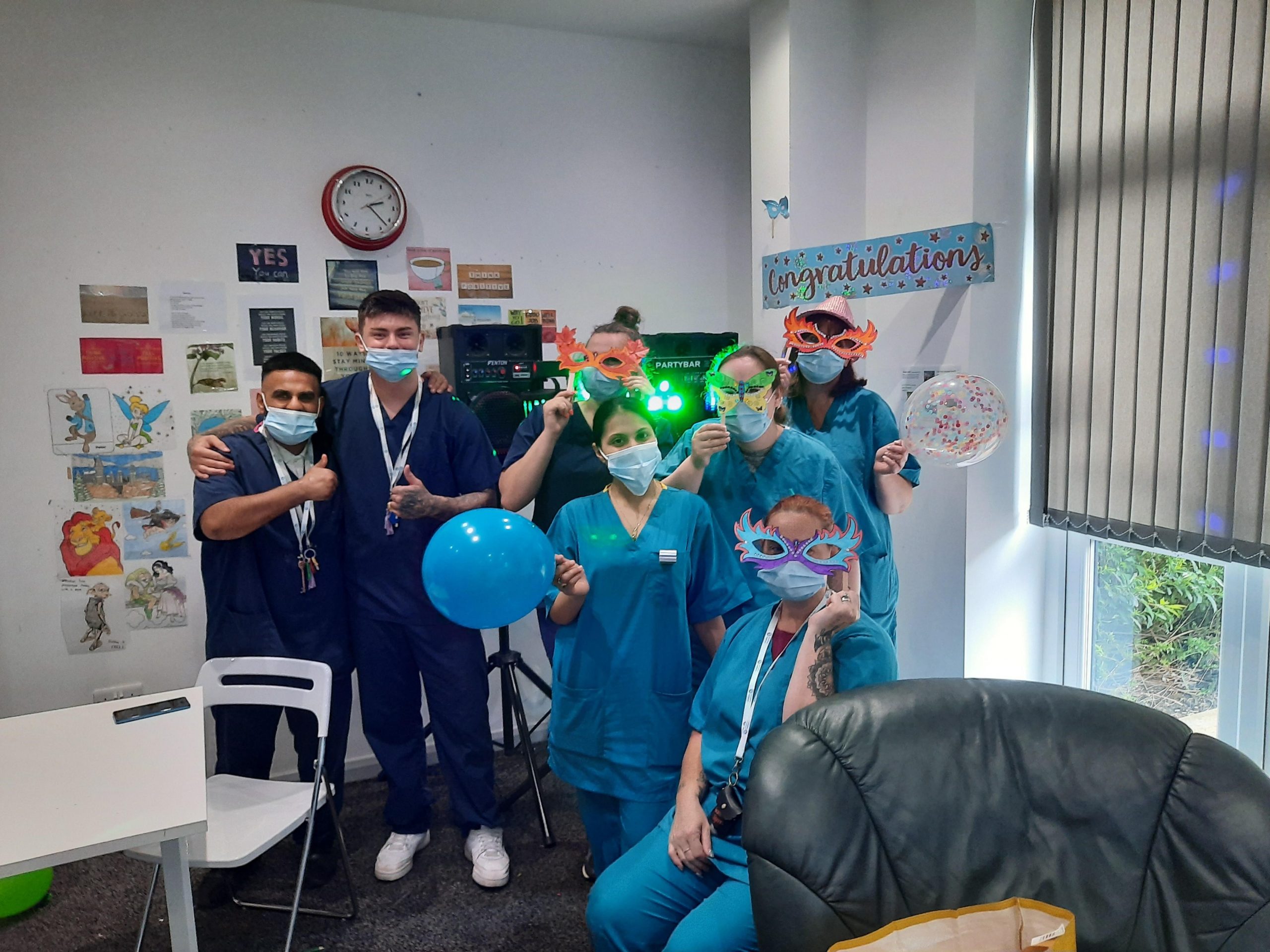 team members posing with congratulations banners and balloons