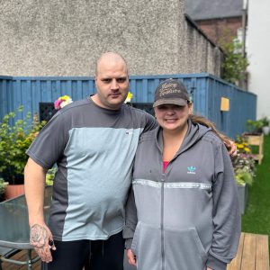 Two people we support at Montgomery House in Bury, Greater Manchester, pausing for a photo during the garden renovation.