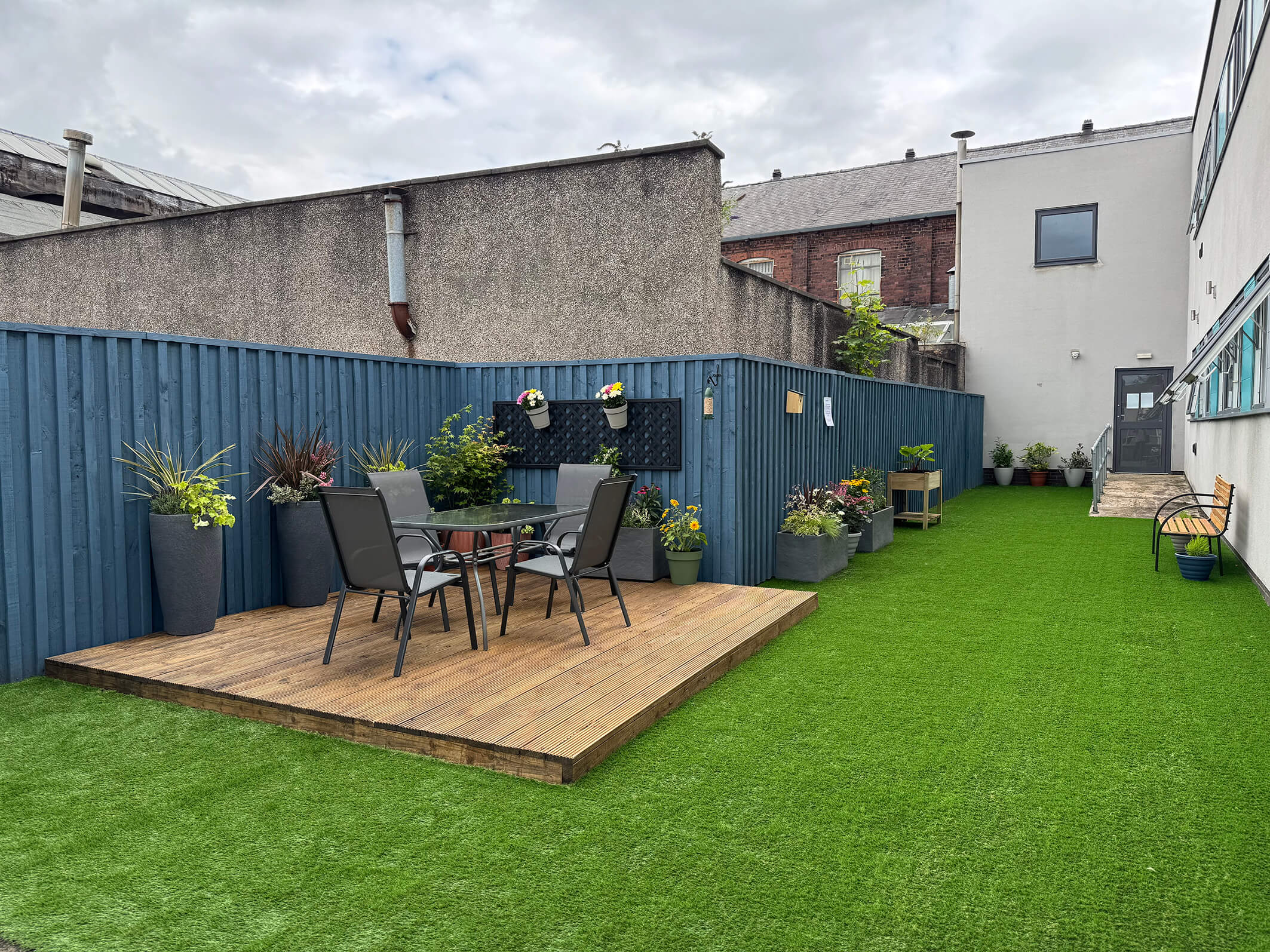 The final result of the garden makeover and renovation at Montgomery House in Bury, Greater Manchester, showing a new patio and garden area with furniture.