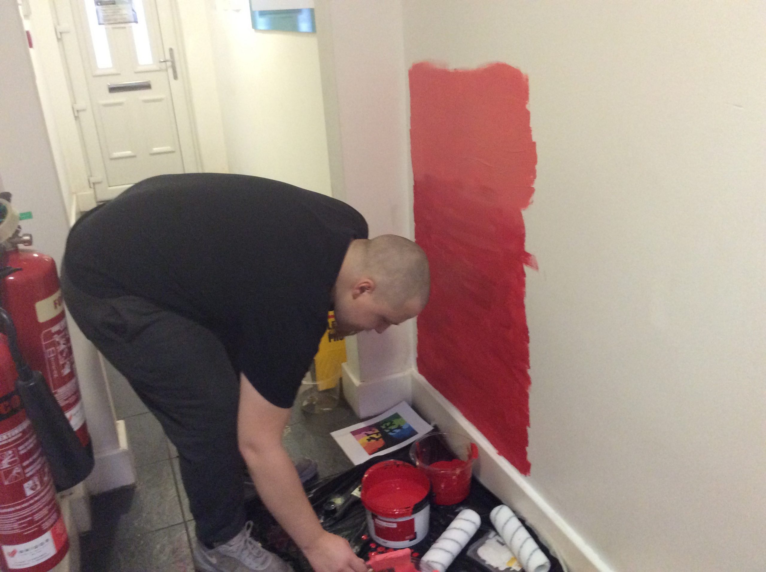 resident painting wall with red paint