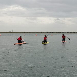 Three people on a lake paddle boarding
