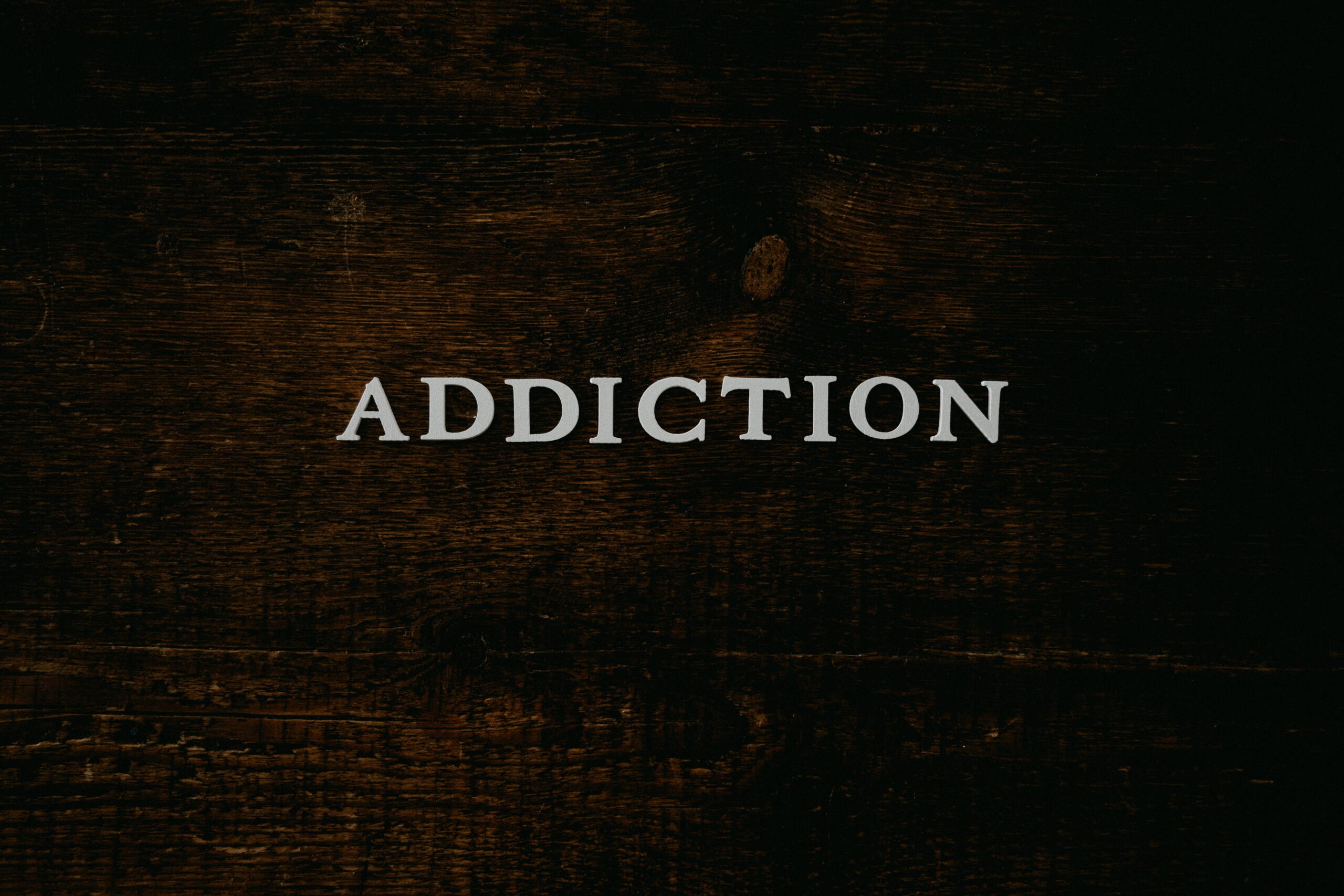 addiction spelled out in white letters on wooden background