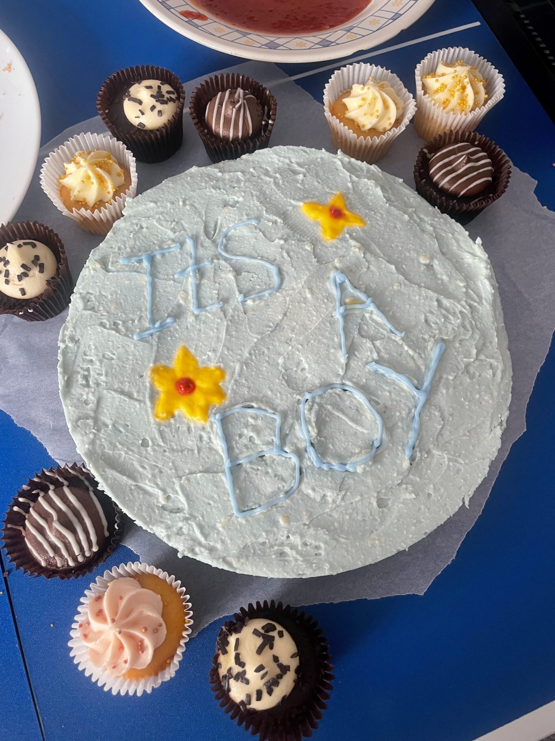 baby shower cake with blue icing reads "it's a boy!"