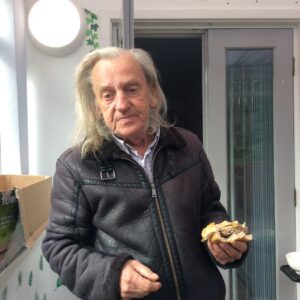 male in black jacket holding burger