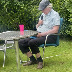 resident sitting in chair doing karaoke in garden
