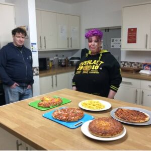 Resident with Halloween face paint displaying pizzas