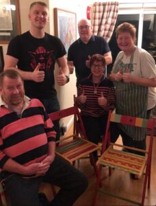 family posing with upcycled chairs restored by Radcliffe House residents