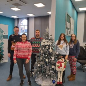 HO staff wearing christmas jumpers by the christmas tree