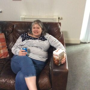 smiling female sitting on couch holding easter egg and can of pepsi