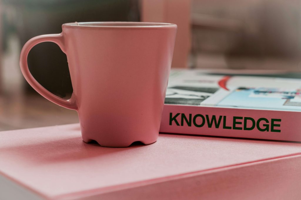 Mug next to a book titled "knowledge" for a blog on challenging and debunking myths around supported living.