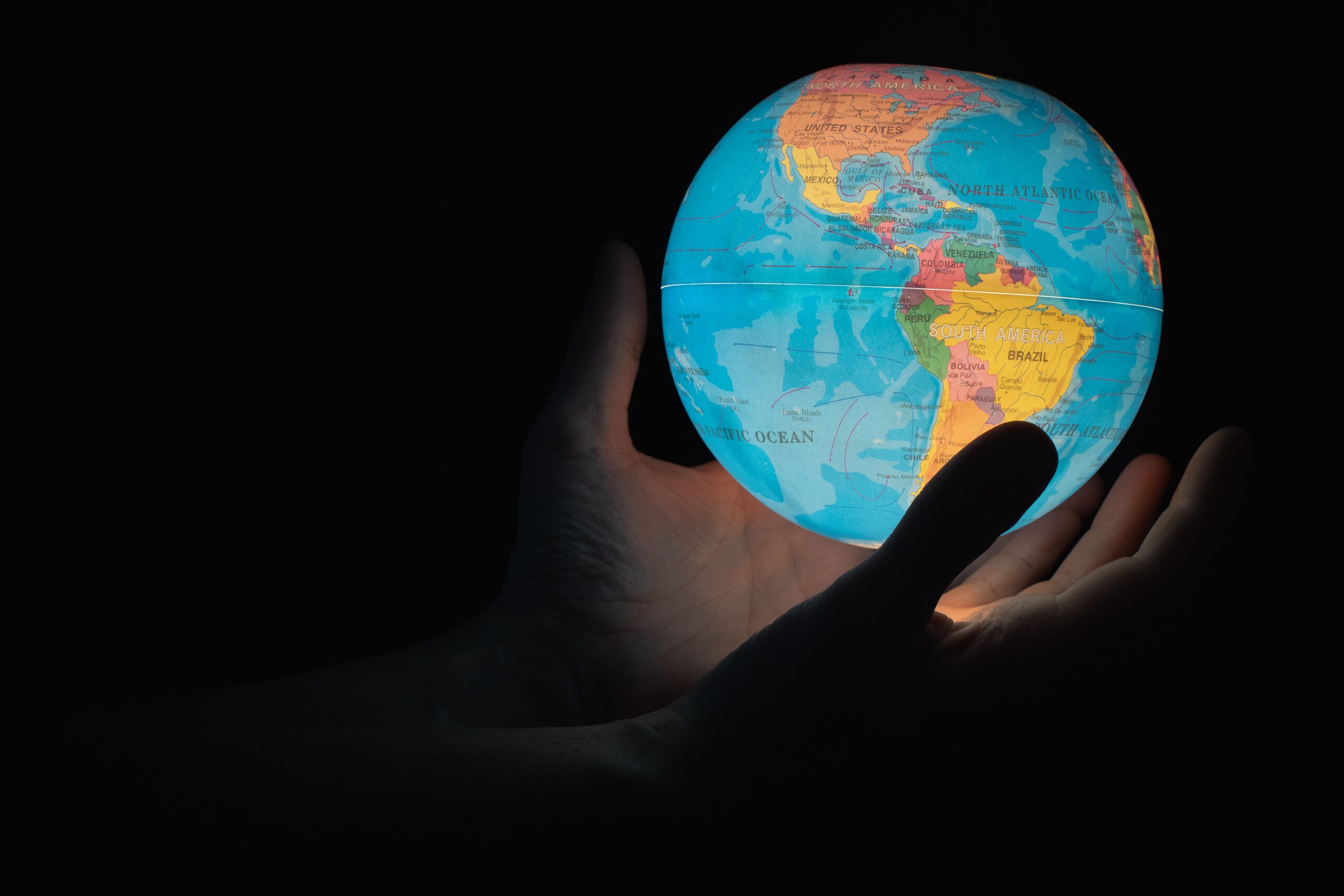 silhouette of hand holding illuminated globe