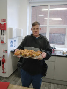 resident holding tray of homemade haggis sausage rolls