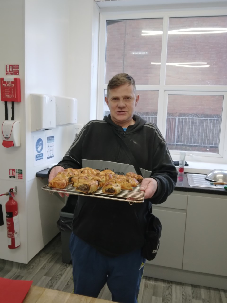 resident holding tray of homemade haggis sausage rolls
