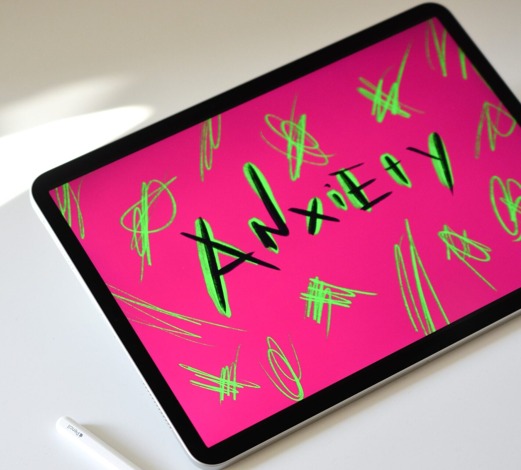 tablet with screen displaying word anxiety on bright pink background with green doodles