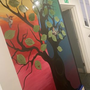wall display with rainbow background, brown tree and green leaves filled with quotes