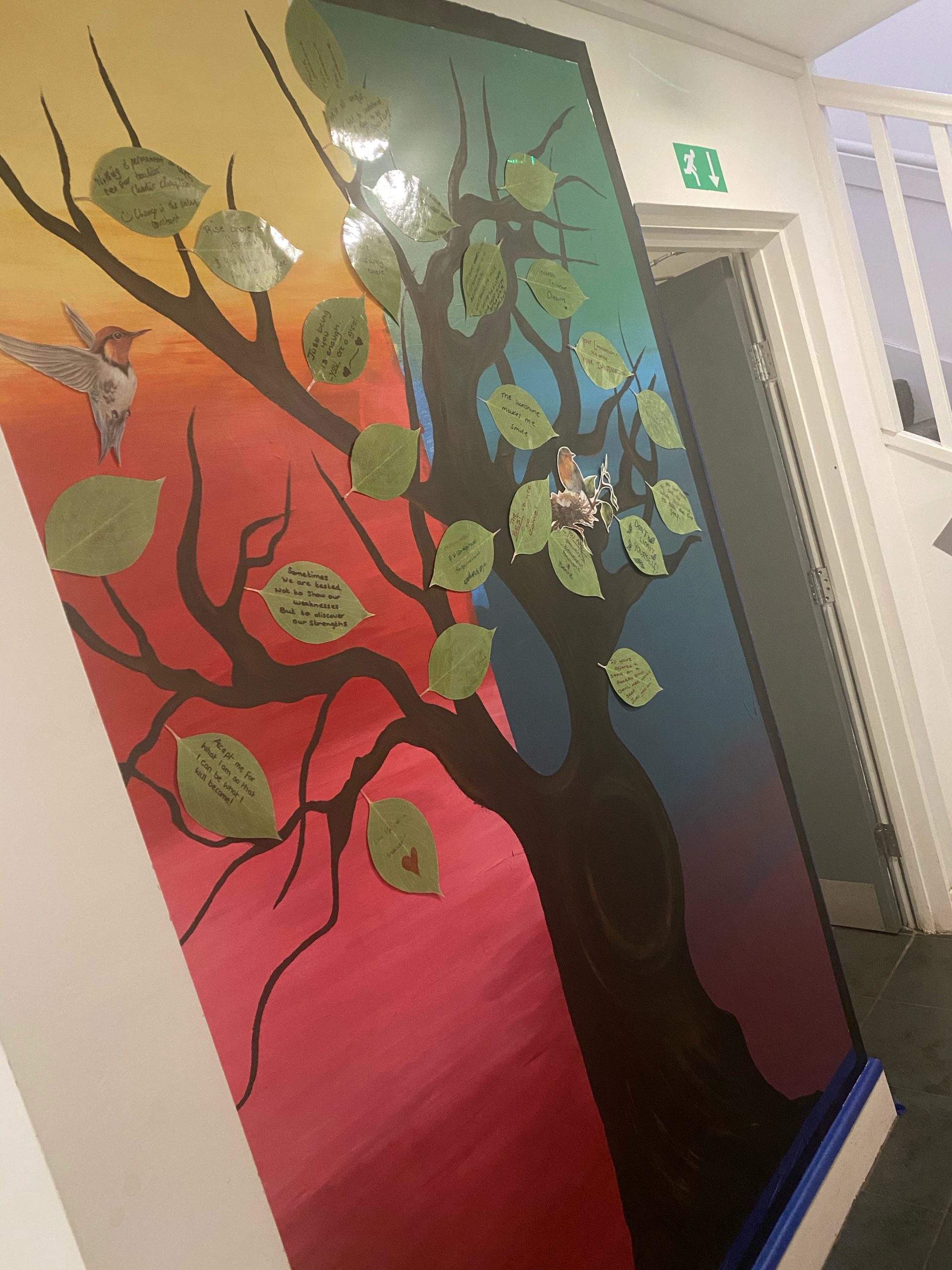 wall display with rainbow background, brown tree and green leaves filled with quotes
