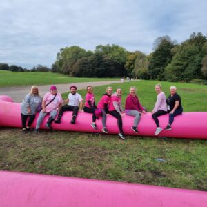 the team climbing over an inflatable pink tube