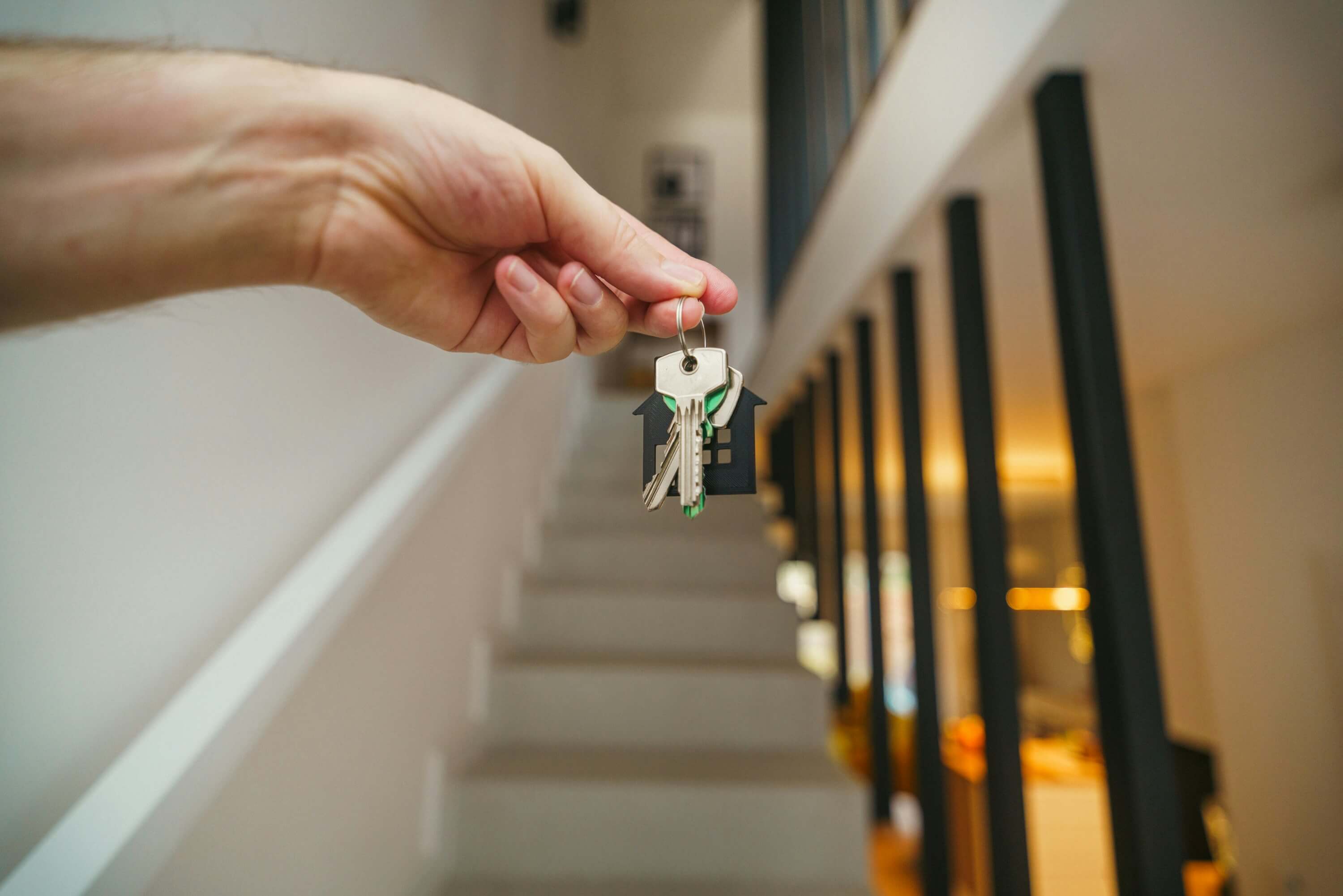 Hallway with hands holding out a pair of keys to represent transitions in mental health and social care settings.