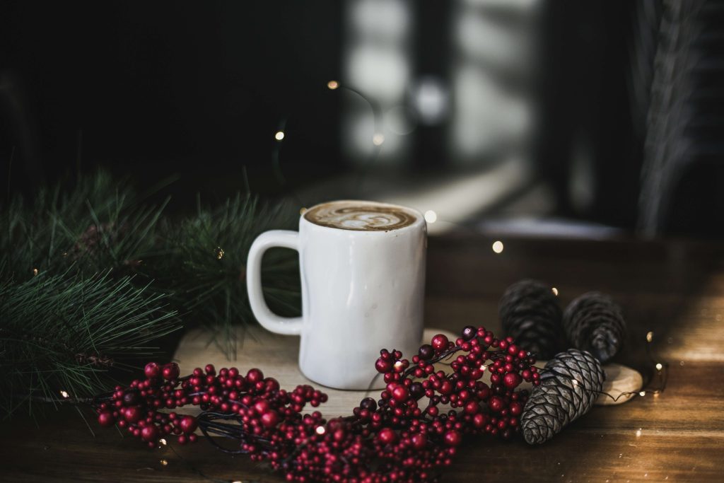A hot drink in a white mug in a cosy. Christmas-inspired setting for a blog about mindful things to do in winter.