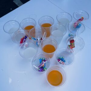 plastic cups in pyramid shape - half filled with juice, half filled with sweets