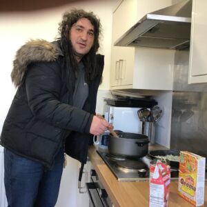 male resident stirring curry on pan