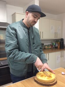male slicing lemon tart in half with knife