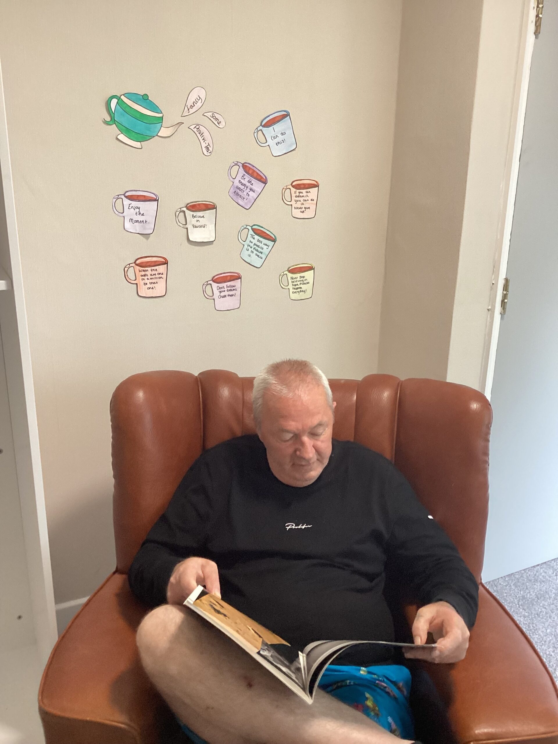 male resident reading book in red armchair