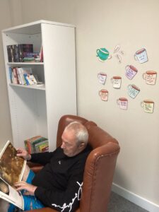 male resident reading book in red armchair