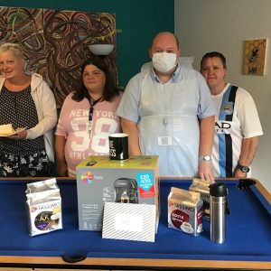 team member and residents posing with coffee machine
